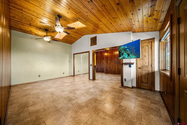 spare room with ceiling fan, wooden ceiling, and vaulted ceiling with skylight