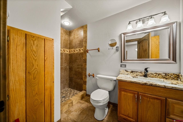 bathroom with vanity, toilet, and tiled shower