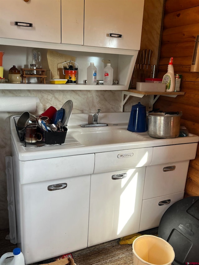 kitchen featuring wooden walls and white cabinets