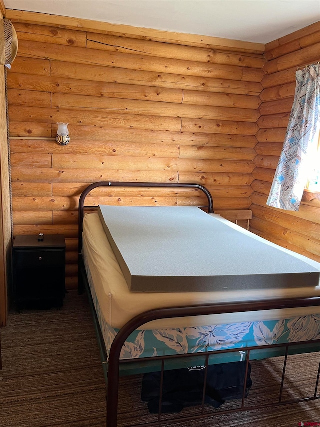 unfurnished bedroom with log walls and dark carpet