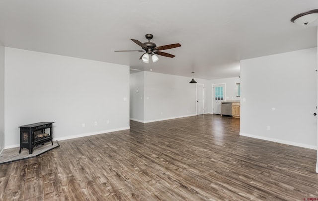 unfurnished living room featuring dark wood-type flooring, ceiling fan, and a wood stove