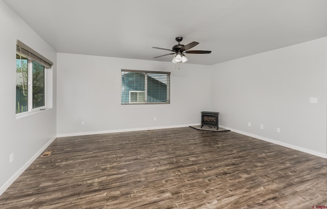 spare room featuring a wood stove, ceiling fan, and dark hardwood / wood-style flooring