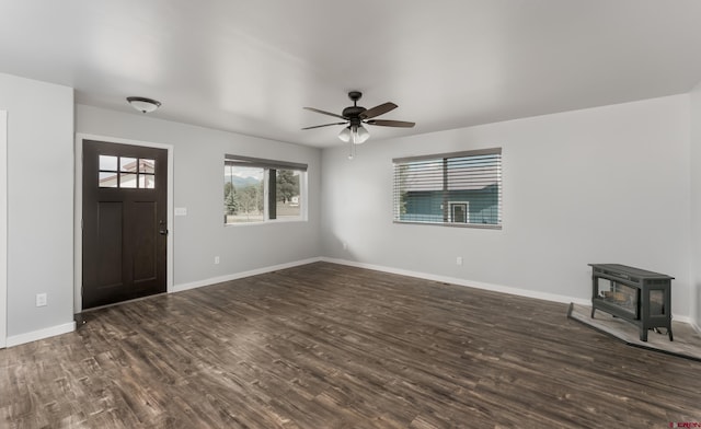 foyer with a wood stove, ceiling fan, and dark hardwood / wood-style flooring