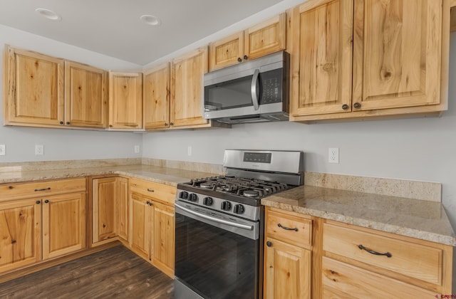 kitchen with light stone countertops, light brown cabinets, stainless steel appliances, and dark hardwood / wood-style floors