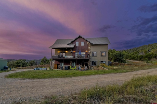 view of front of home featuring a balcony and a yard