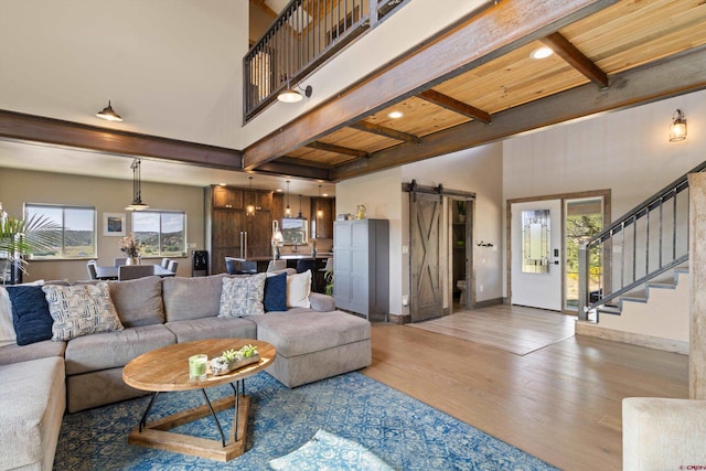 living room with hardwood / wood-style flooring, a barn door, wood ceiling, beamed ceiling, and a high ceiling