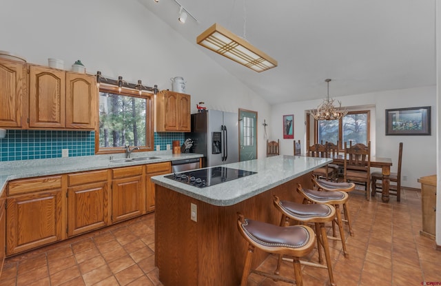 kitchen featuring a kitchen island, pendant lighting, a notable chandelier, stainless steel fridge with ice dispenser, and sink