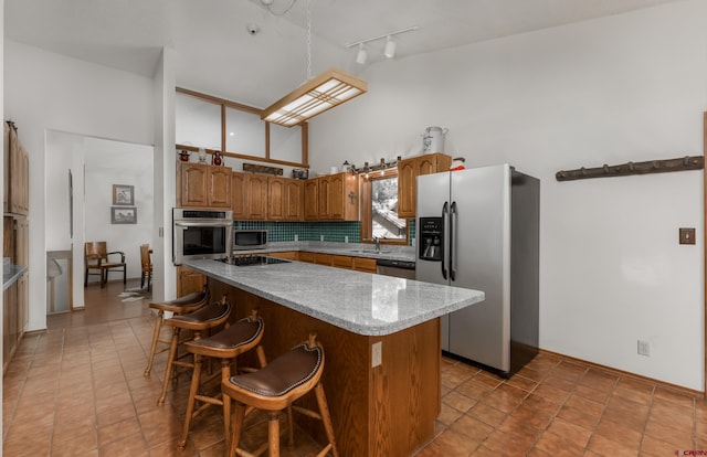 kitchen with stainless steel appliances, a center island, decorative backsplash, a breakfast bar, and light tile patterned flooring