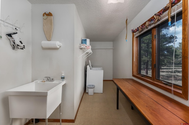 clothes washing area featuring a textured ceiling, washer / clothes dryer, and sink