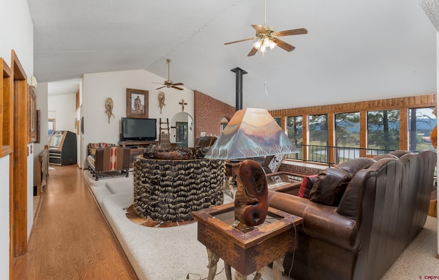 living room with lofted ceiling, light hardwood / wood-style flooring, ceiling fan, and a wood stove