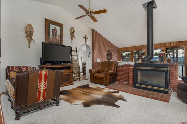 carpeted living room featuring a textured ceiling, high vaulted ceiling, a wood stove, and ceiling fan