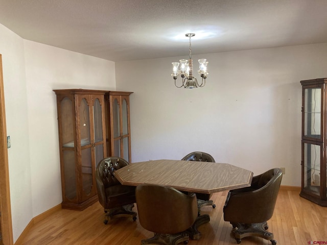 dining space featuring a textured ceiling, an inviting chandelier, and light hardwood / wood-style floors