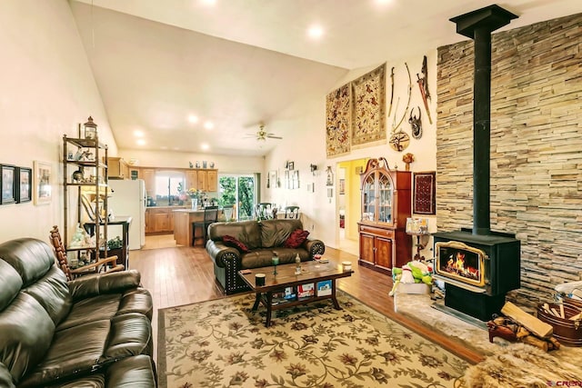 living room with a wood stove, ceiling fan, light wood-type flooring, and lofted ceiling