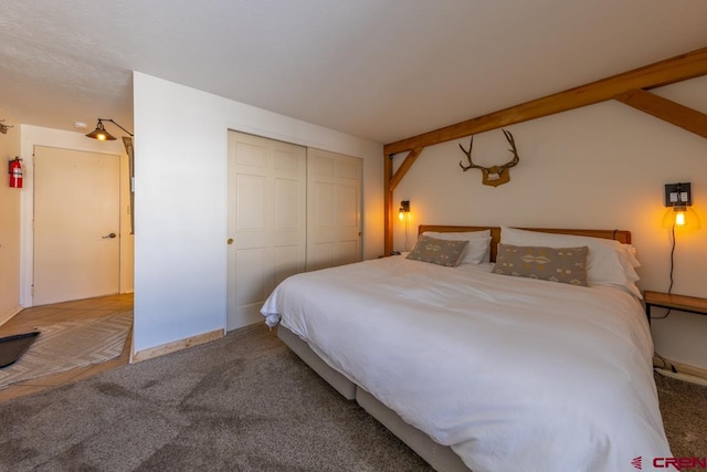 bedroom featuring carpet floors, vaulted ceiling with beams, and a closet