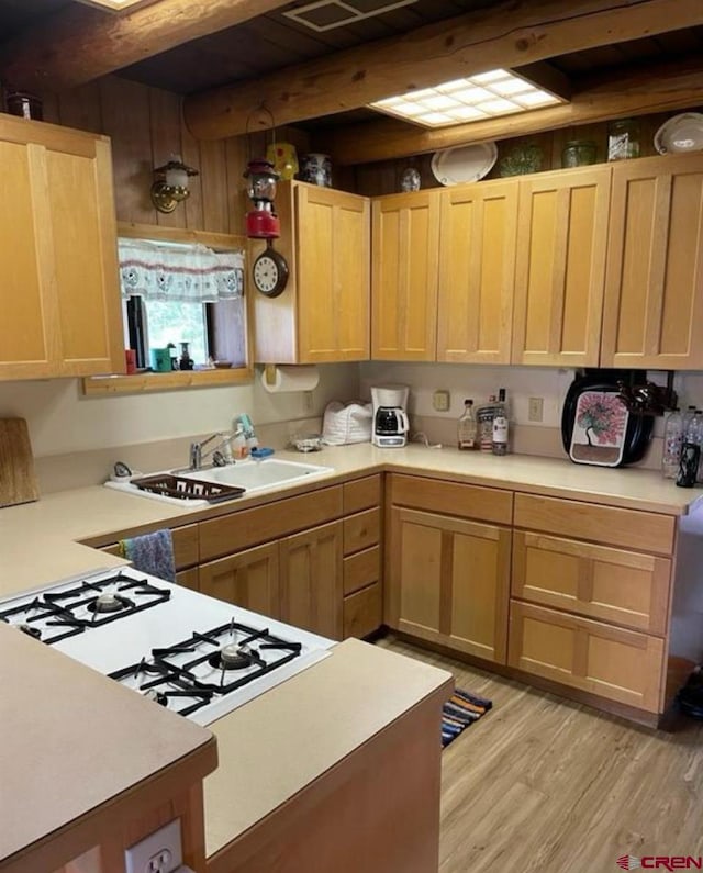 kitchen featuring light hardwood / wood-style flooring, light brown cabinets, beamed ceiling, and sink