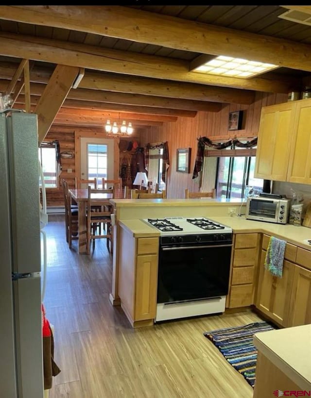 kitchen with white appliances, beamed ceiling, light wood-type flooring, wooden walls, and a chandelier