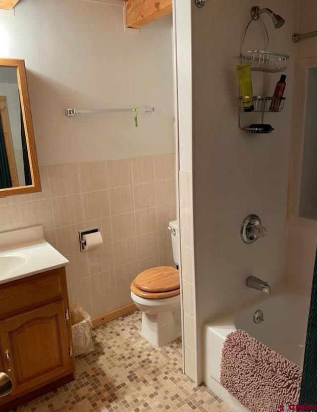 full bathroom with tile walls, vanity, toilet, and tile patterned floors