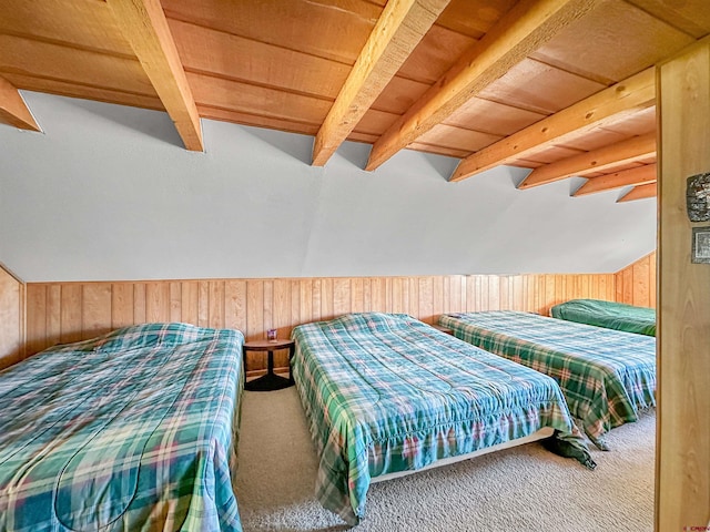 carpeted bedroom with beam ceiling and wood walls