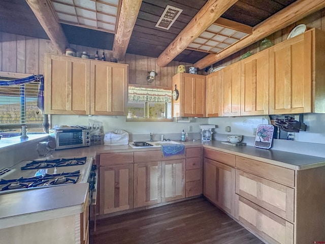 kitchen with beam ceiling, light brown cabinets, and gas range gas stove