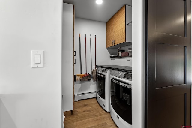 clothes washing area with cabinets, light hardwood / wood-style floors, a baseboard radiator, and washing machine and clothes dryer