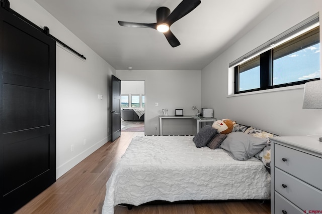 bedroom featuring ceiling fan, dark wood-type flooring, and a barn door