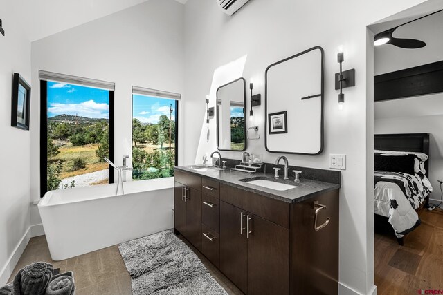 bathroom featuring hardwood / wood-style floors, a bath, vanity, and vaulted ceiling