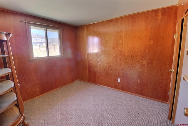 carpeted empty room featuring wood walls