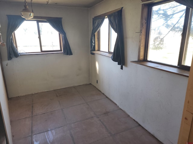 tiled empty room featuring plenty of natural light