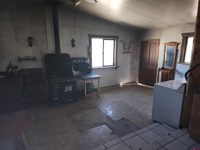 living room featuring a wood stove, vaulted ceiling, and concrete flooring