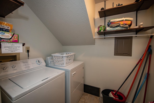 laundry room with washing machine and clothes dryer, a textured ceiling, electric panel, and light tile patterned floors