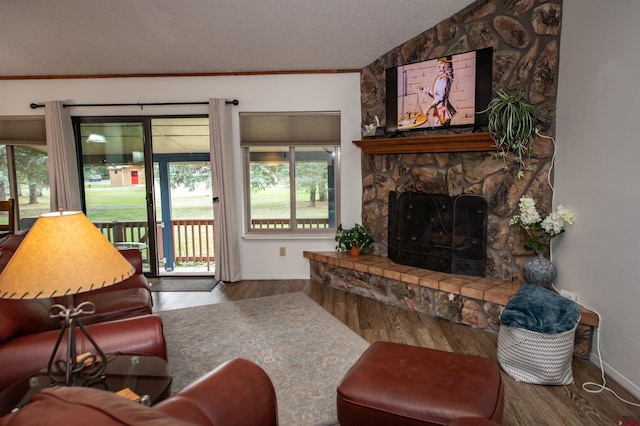 living room with wood-type flooring, a textured ceiling, a fireplace, and lofted ceiling