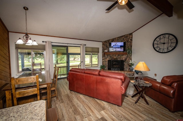 living room featuring a stone fireplace, ceiling fan with notable chandelier, plenty of natural light, and lofted ceiling with beams