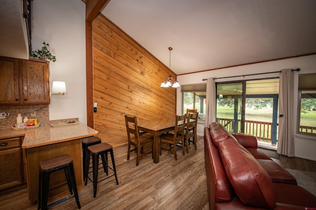 dining area featuring a healthy amount of sunlight, wooden walls, and a chandelier