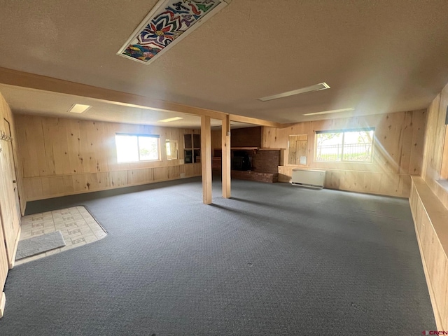 basement featuring carpet floors, a textured ceiling, and wooden walls