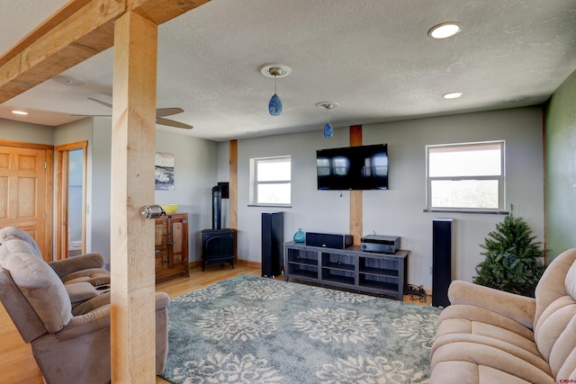 living room with ceiling fan, hardwood / wood-style floors, a wood stove, and a wealth of natural light