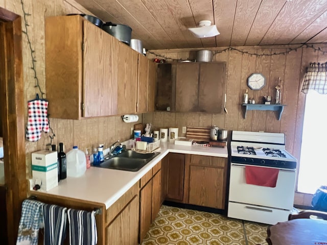 kitchen featuring white gas range oven, wooden ceiling, a healthy amount of sunlight, and sink