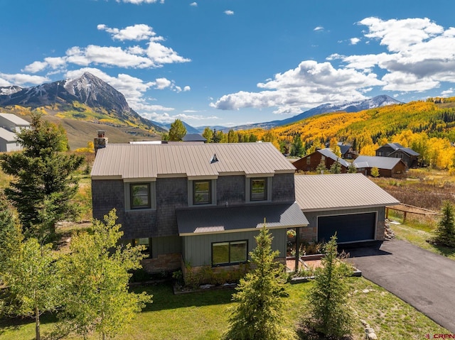 view of front of home featuring a mountain view, a front yard, and a garage