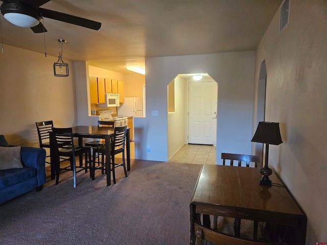 dining space with arched walkways, light carpet, ceiling fan, and visible vents