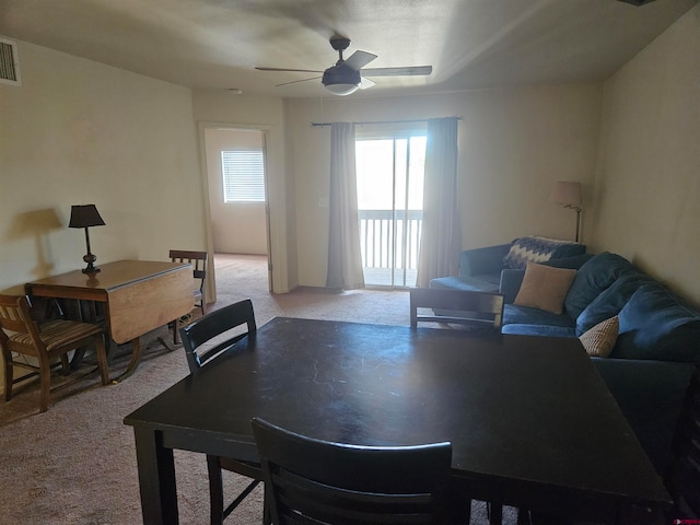 dining space with a ceiling fan and light carpet