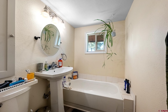 bathroom featuring a textured ceiling, toilet, and a tub