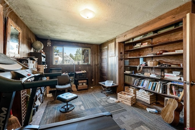 office area featuring a textured ceiling, wood walls, and carpet