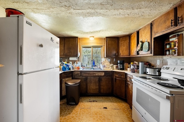 kitchen with white appliances, a textured ceiling, and sink