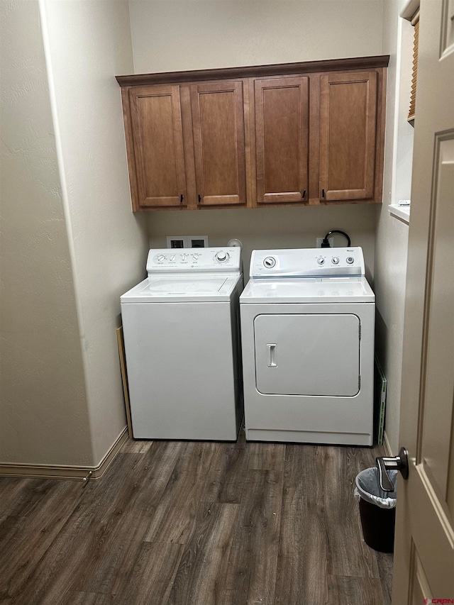 clothes washing area featuring cabinets, dark wood-type flooring, and washing machine and clothes dryer