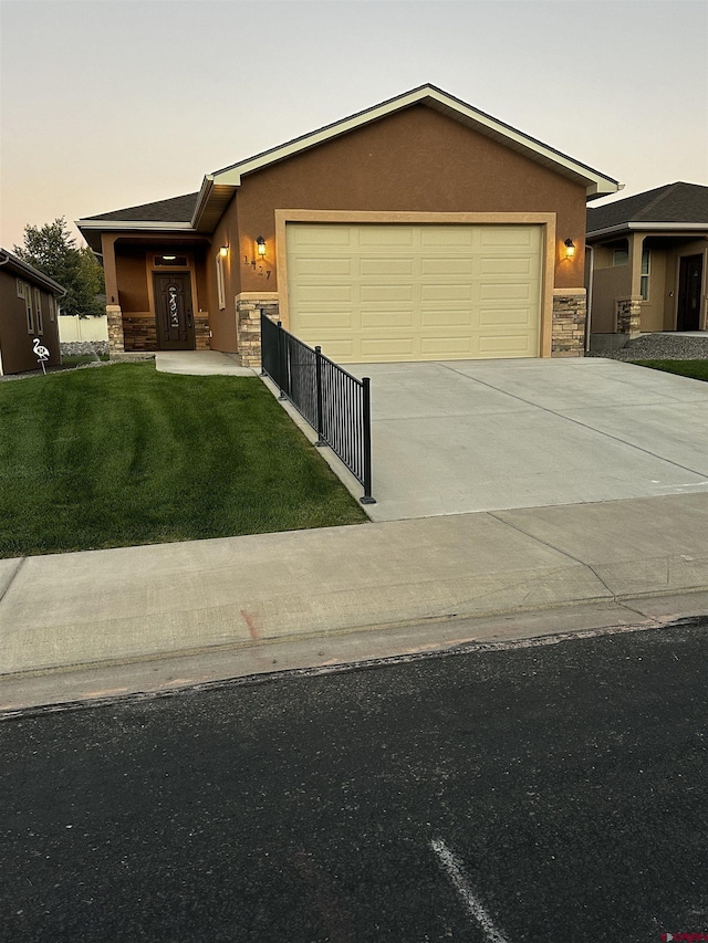 1427 Rainier Ln, Delta, CO 81416 - view of front of home featuring stone siding, a garage, concrete driveway, a front yard, and stucco siding