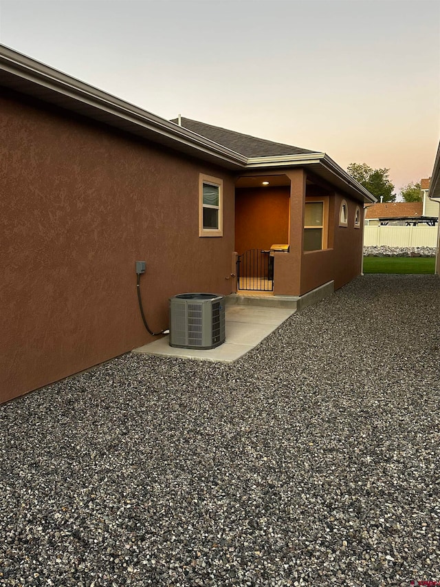 back house at dusk featuring a patio and central AC unit