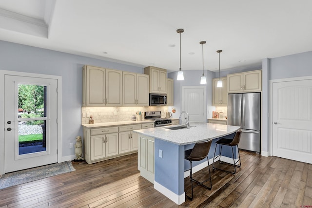 kitchen featuring appliances with stainless steel finishes, hanging light fixtures, a kitchen breakfast bar, an island with sink, and dark hardwood / wood-style floors