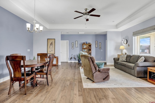 living room with ceiling fan with notable chandelier, crown molding, a raised ceiling, and light hardwood / wood-style flooring