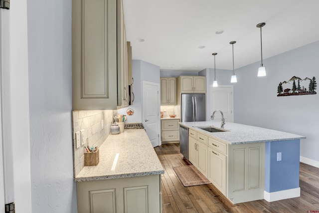 kitchen with appliances with stainless steel finishes, hardwood / wood-style floors, sink, and an island with sink