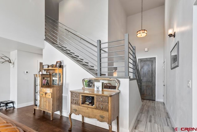 stairway featuring wood-type flooring and a towering ceiling