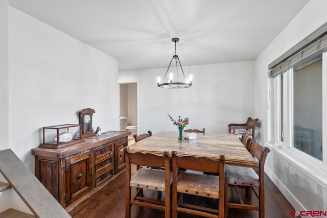 dining area with dark hardwood / wood-style floors and a notable chandelier